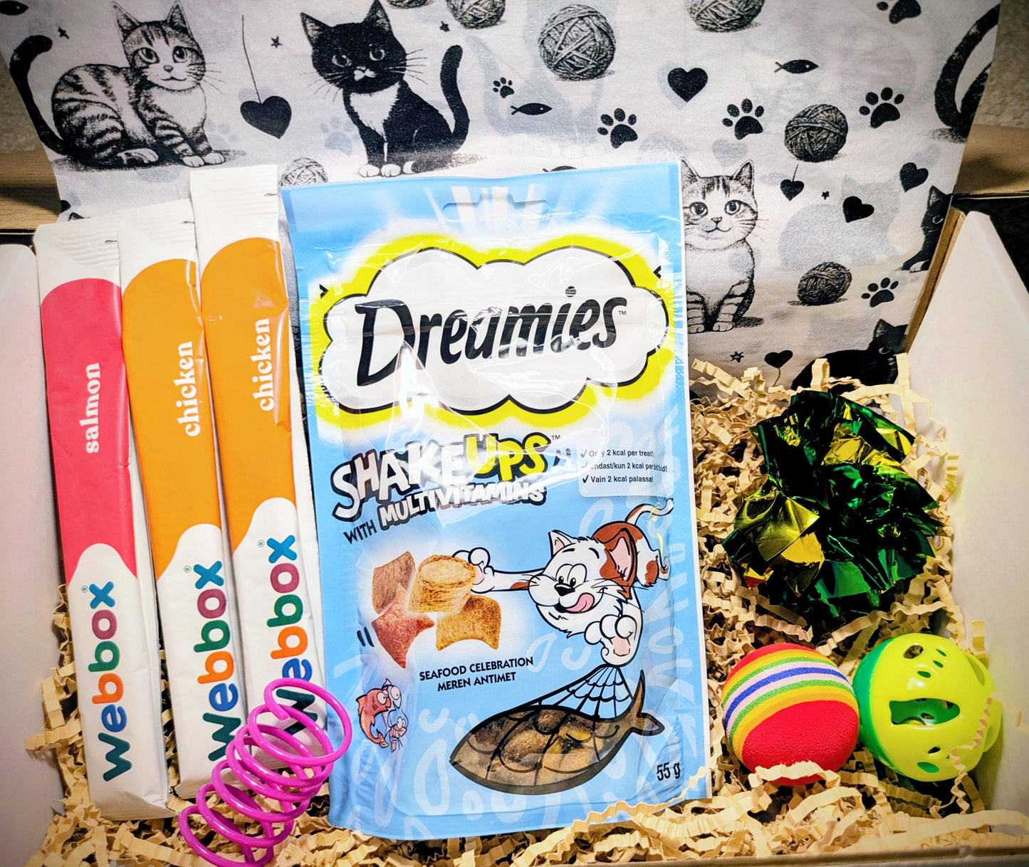 Personalised cat treat box with Dreamies cat snacks, colorful cat toys, and a black-and-white cat-themed gift bag.