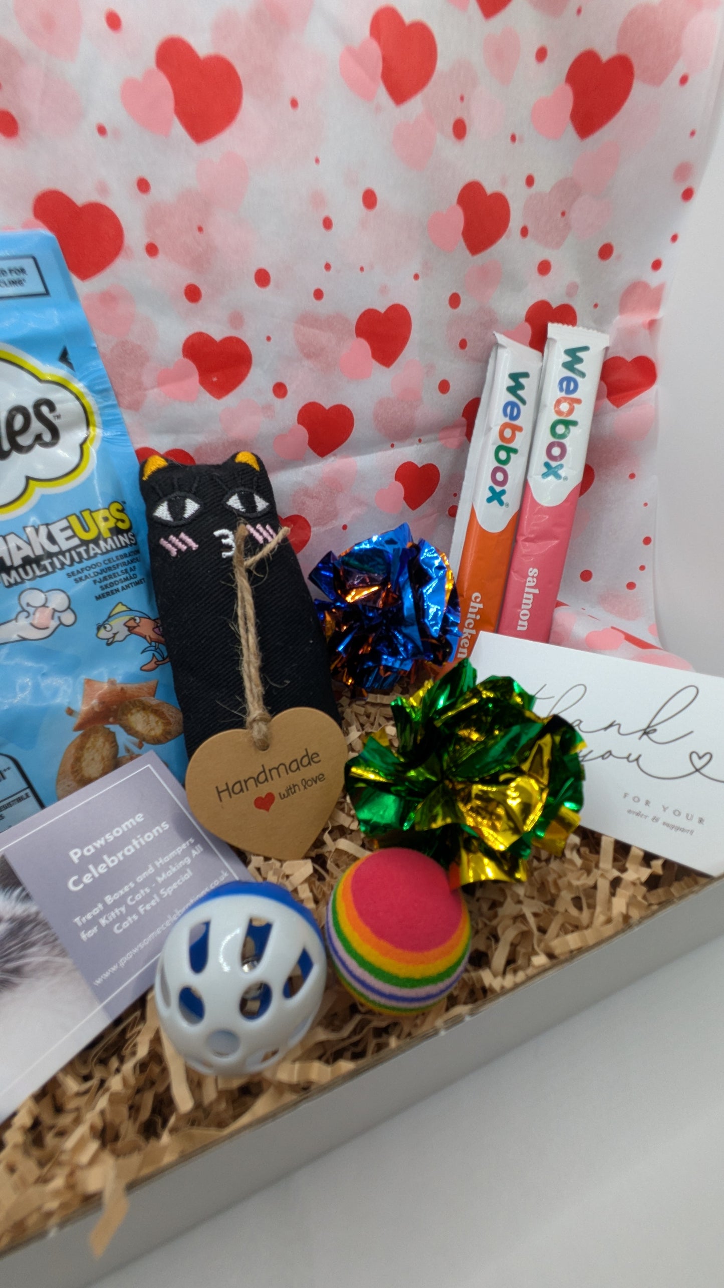 Gift box with pet toys, treats, and accessories on a heart-patterned background