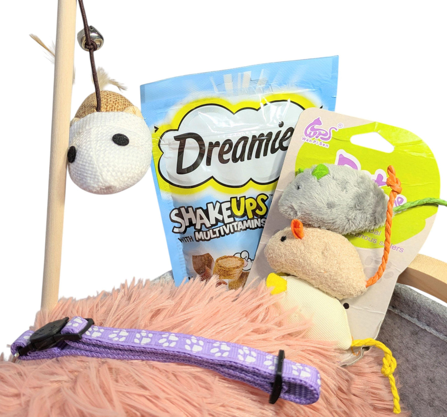Pink plush cat bed with purple collar, mouse wand toy, Dreamies treats, and plush mouse toys in packaging.