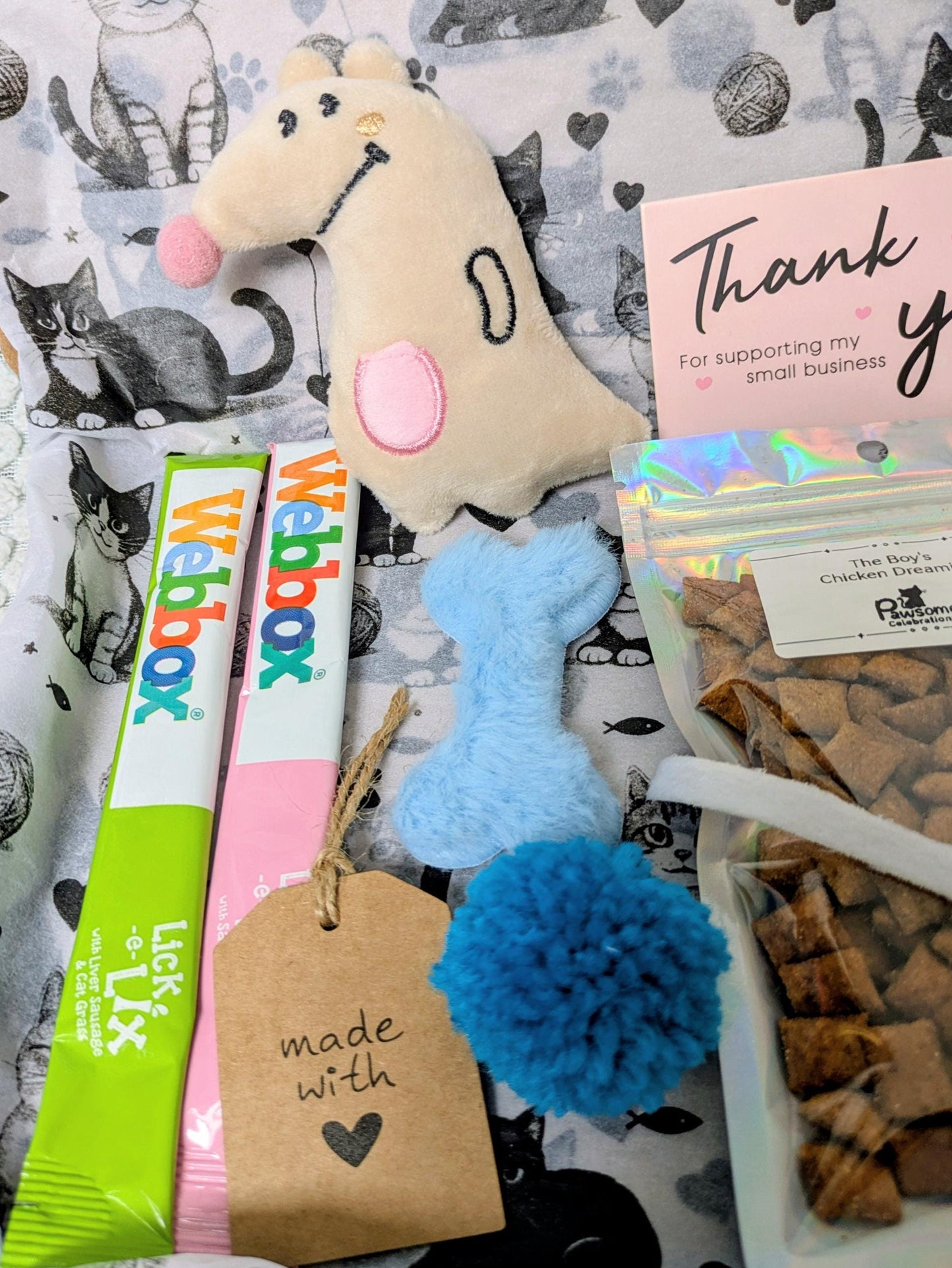 Collection of pet products including a toy, treats, and a box on a patterned background