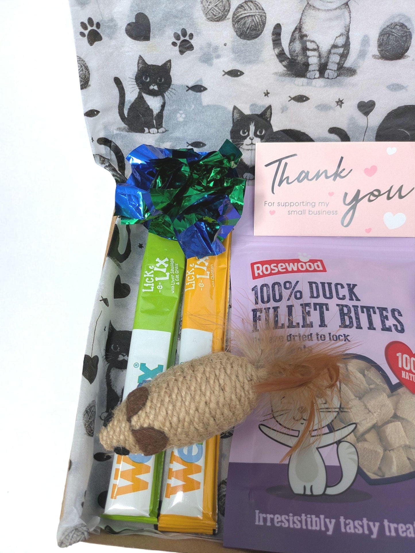 Personalised grain-free cat treat box with black cat print tissue paper, duck fillet bites packet, two wrapped treats, and a .