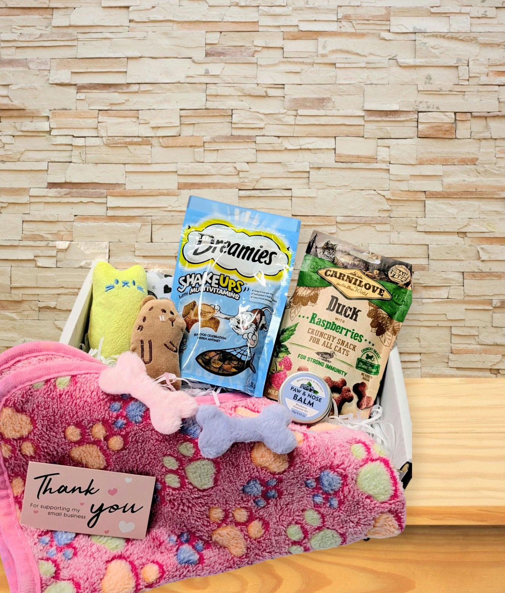 White wooden gift box with personalised cat treat hamper including pink paw-print blanket, plush toys, Dreamies treats, and.