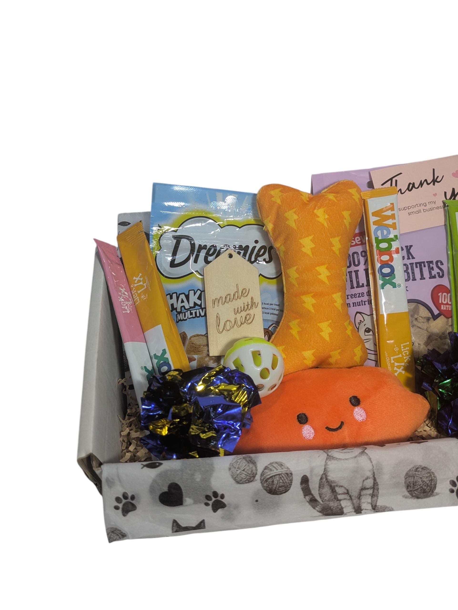 Personalised cat treat hamper with orange bone toy, orange fish toy, treats, and eco-friendly gift box with paw prints.