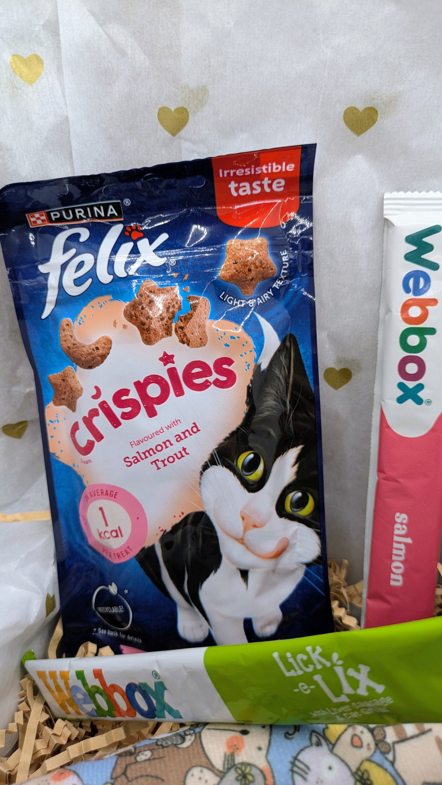 Cat food packages including Felix, Crispies, and Webbox on a white background with heart shapes.