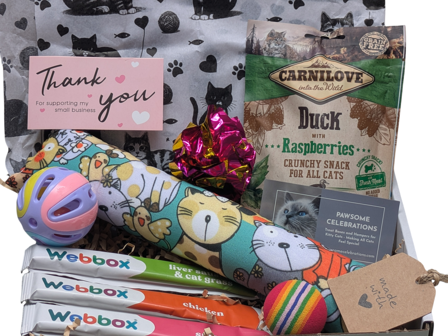 Cat-themed products including a Webbox box, Carnilove cat food, and cat toys on a patterned background.