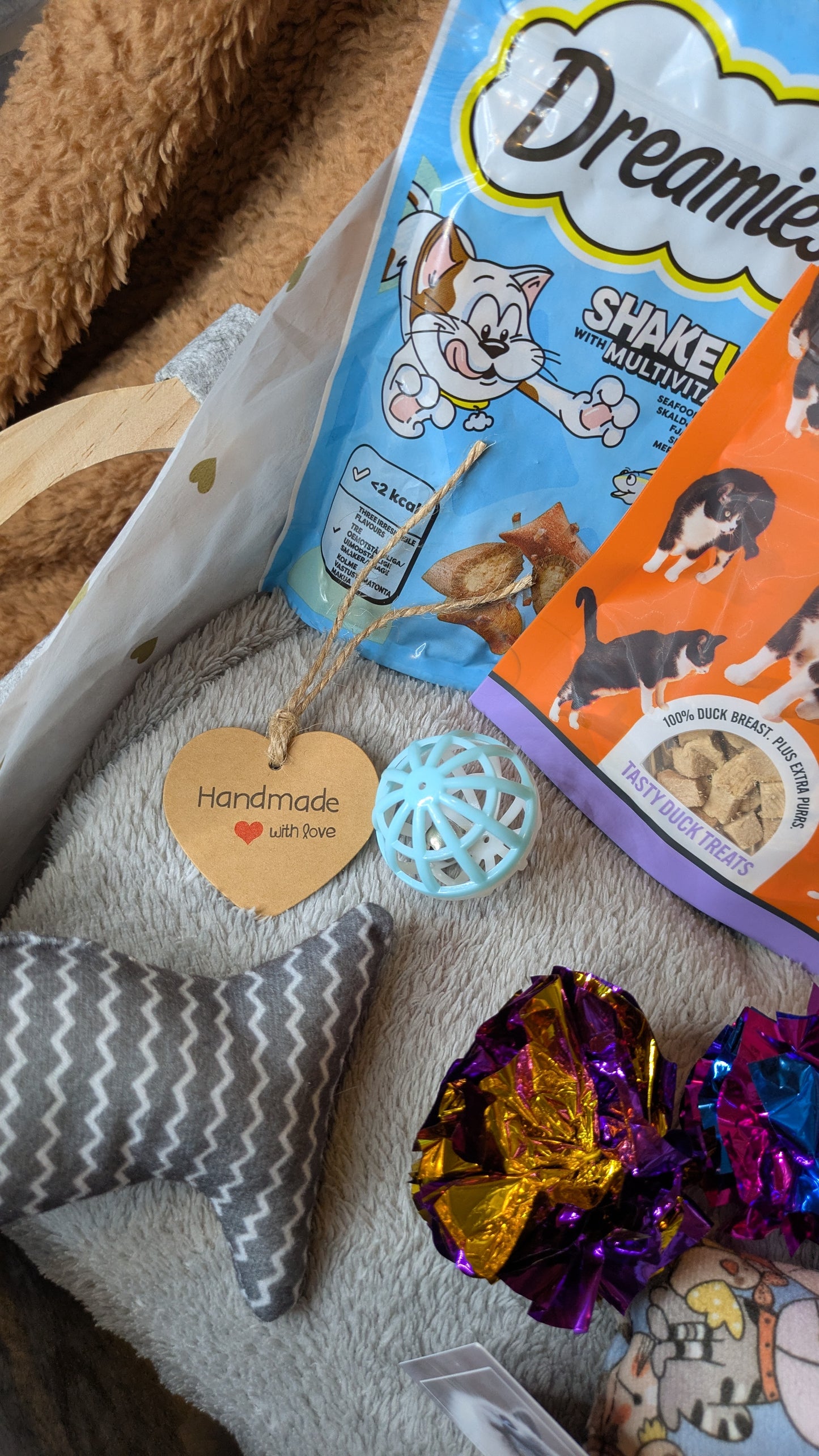 Cat toys and treats on a textured surface with a 'Dreamies' cat treat package.