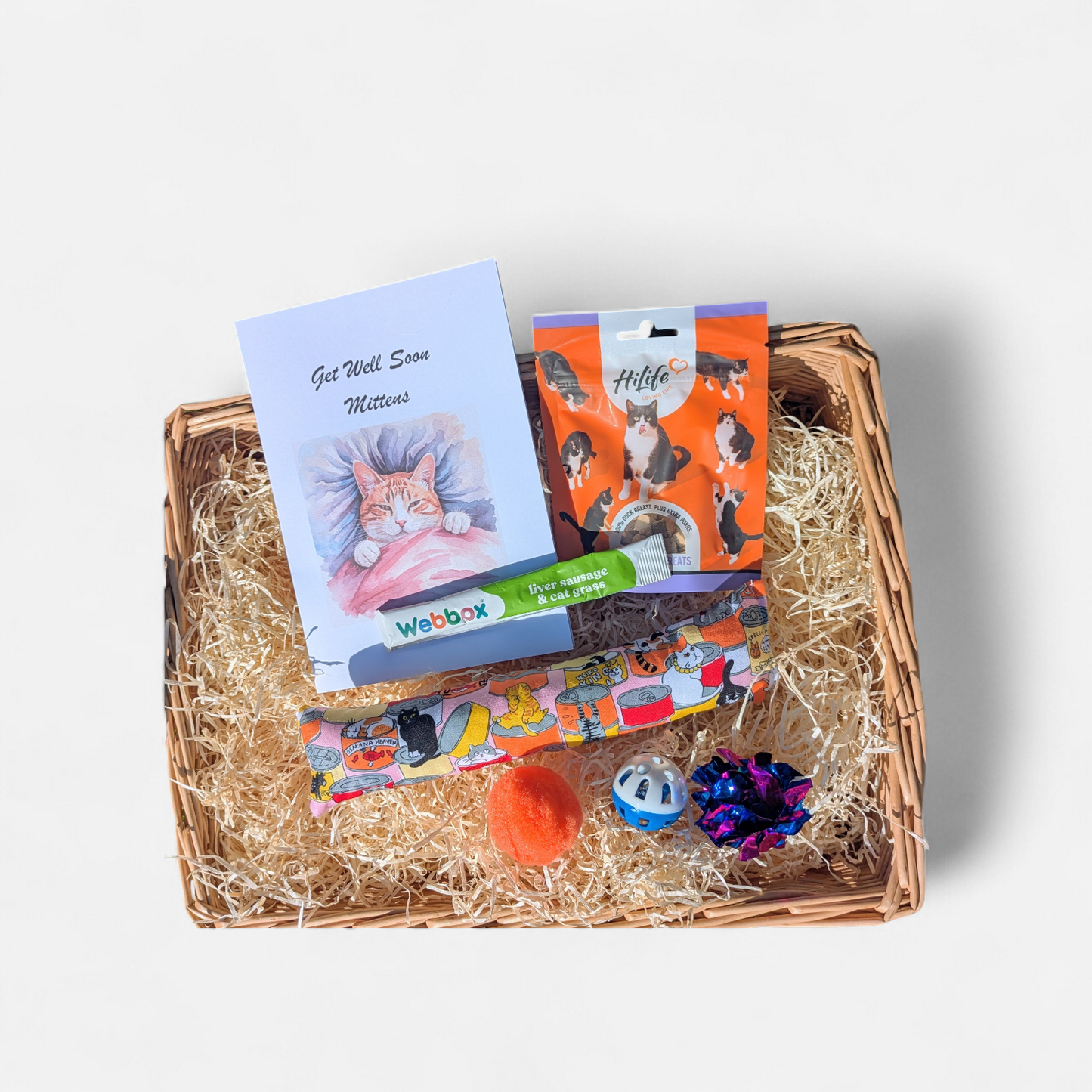 Cat gift basket with various items including a card and toys on a white background