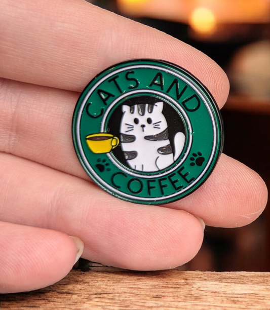 Pin with 'Cats and Coffee' design held between fingers