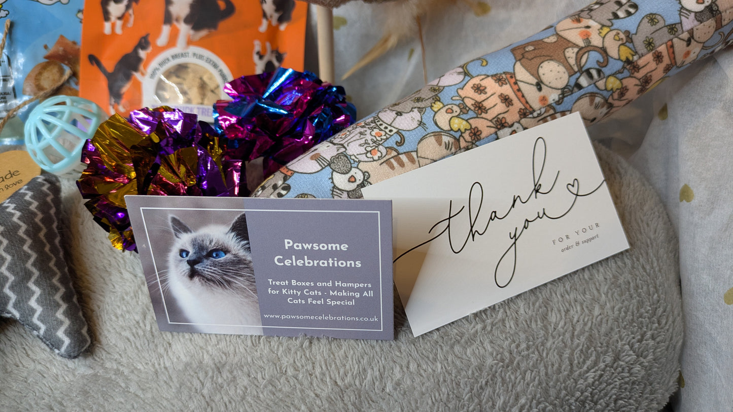 Cat-themed gift with 'Pawsome Celebrations' card and decorative bow on a textured surface.