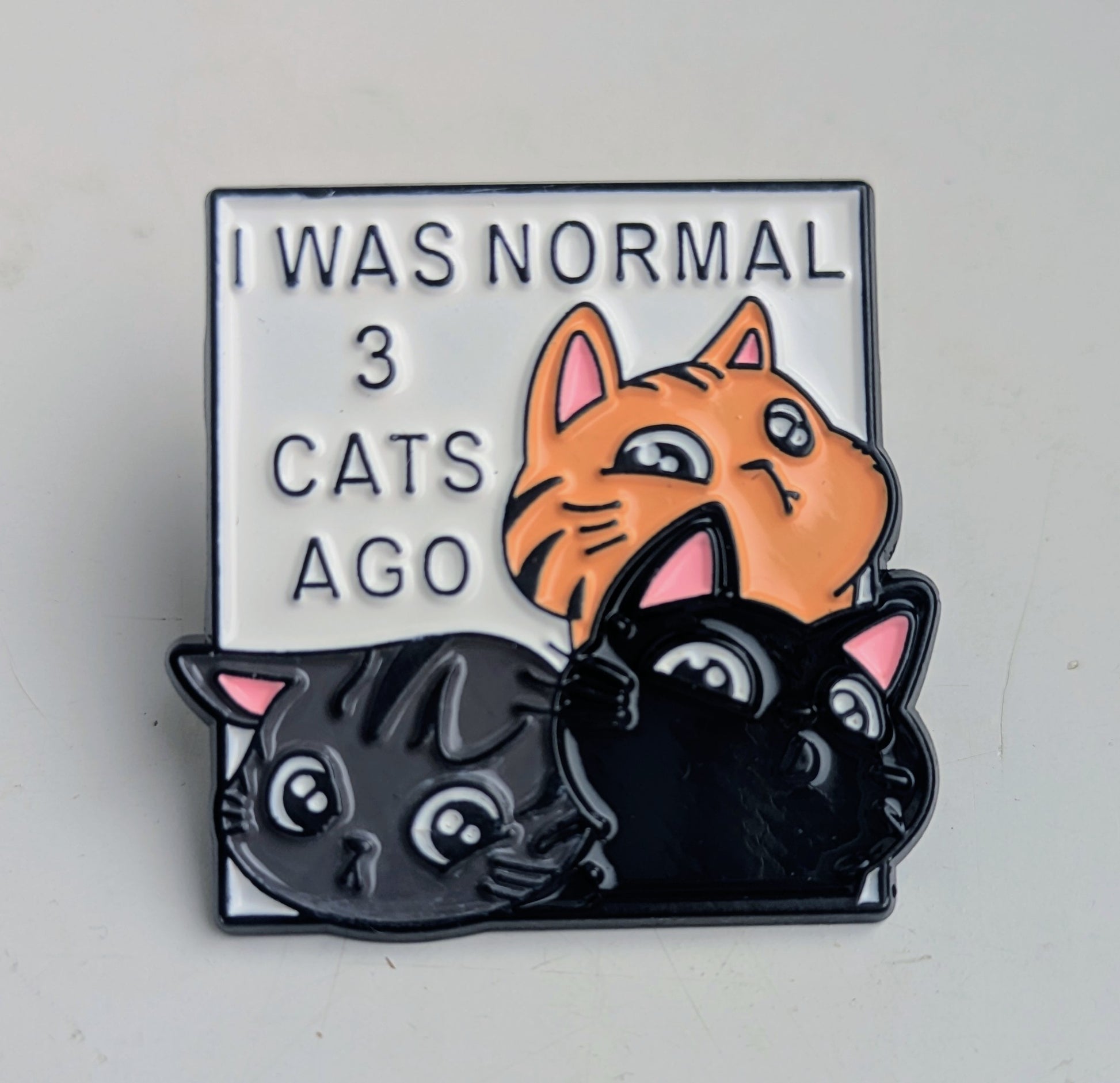 Enamel pin with cartoon cats and text 'I was normal 3 cats ago' on a white background